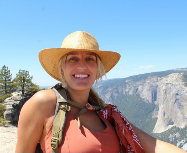 Nancy Karas wearing a straw hat and a backpack with Half Dome in the background